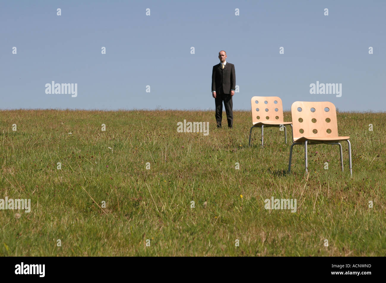 Businessman behind stools on the meadow - Geschäftsman hinter Stühlen auf der Wiese Stock Photo