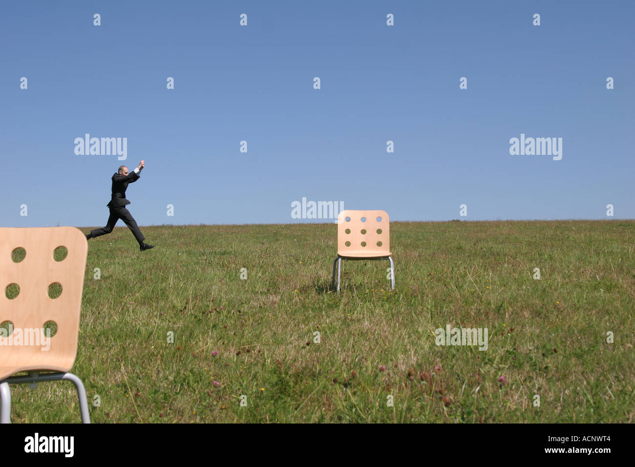 Businessman jumping beetween stools - Sprung eines Geschäftsmann im Freien Stock Photo