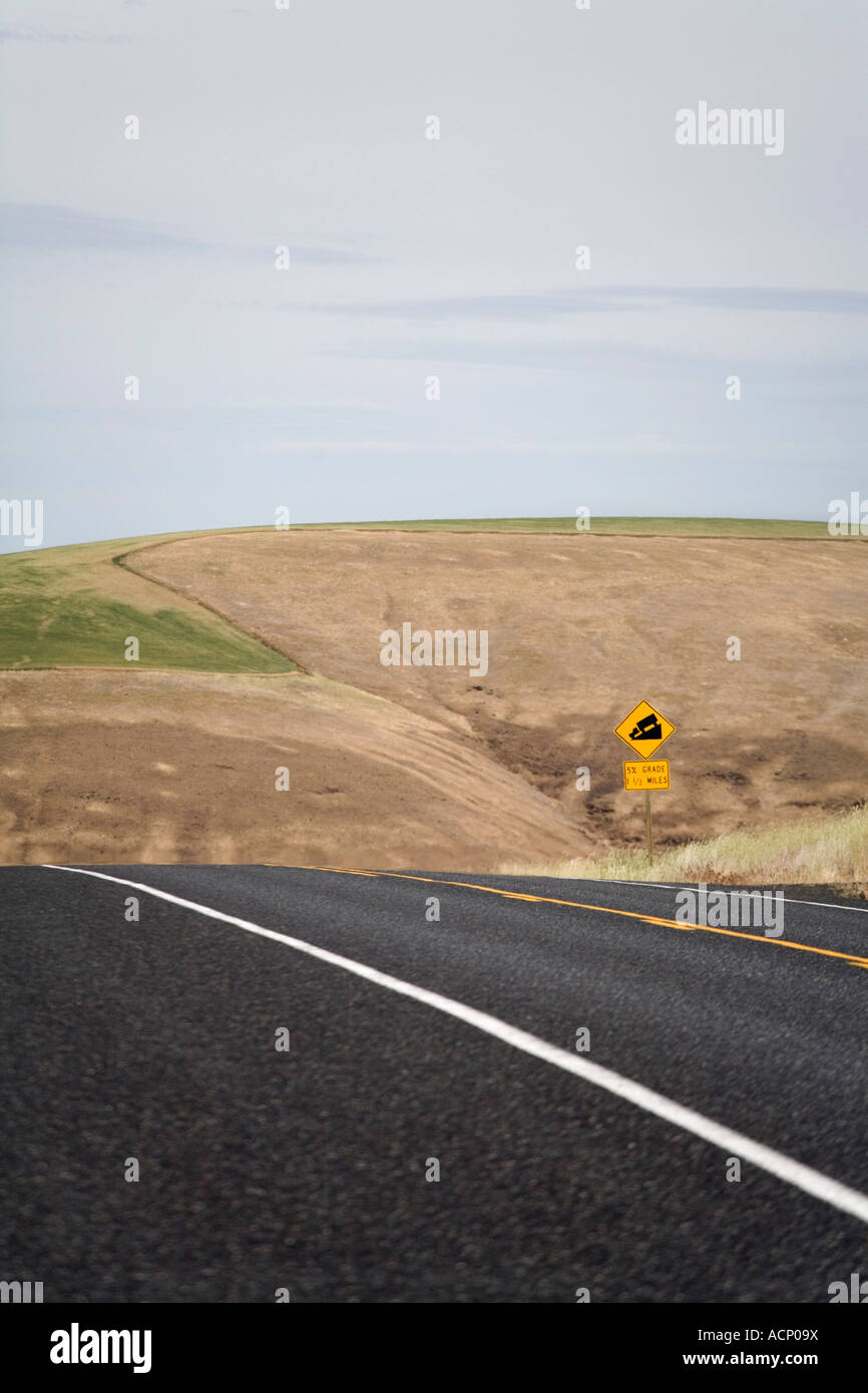 A highway crests a steep hill with sign Stock Photo