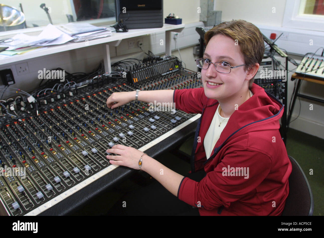 Female student using mixing desk in music studio at Sixth form College ...