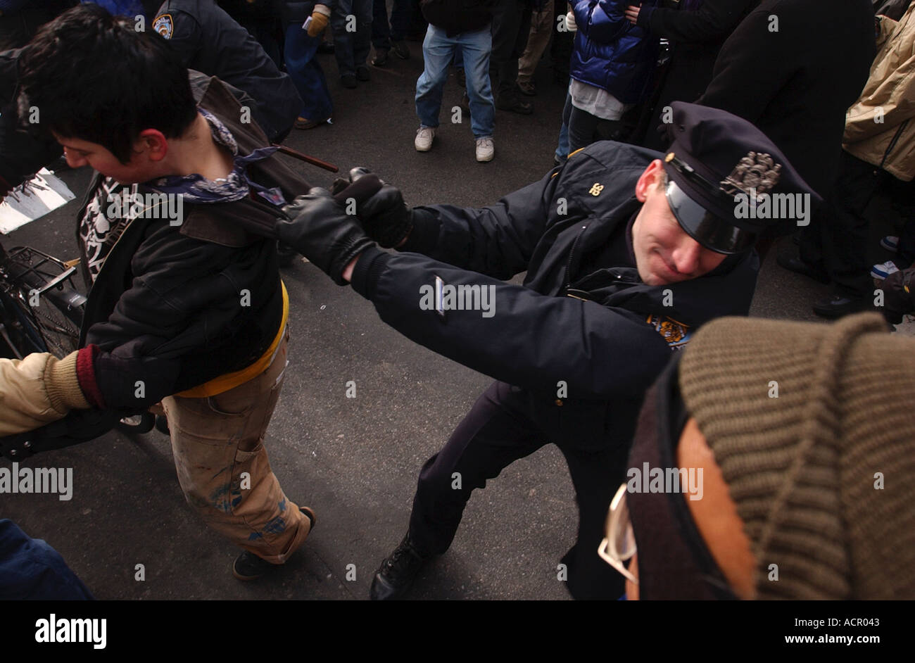 A police officer police man grabs a protester by the collar during a massive protest in New York against the war in Iraq Stock Photo
