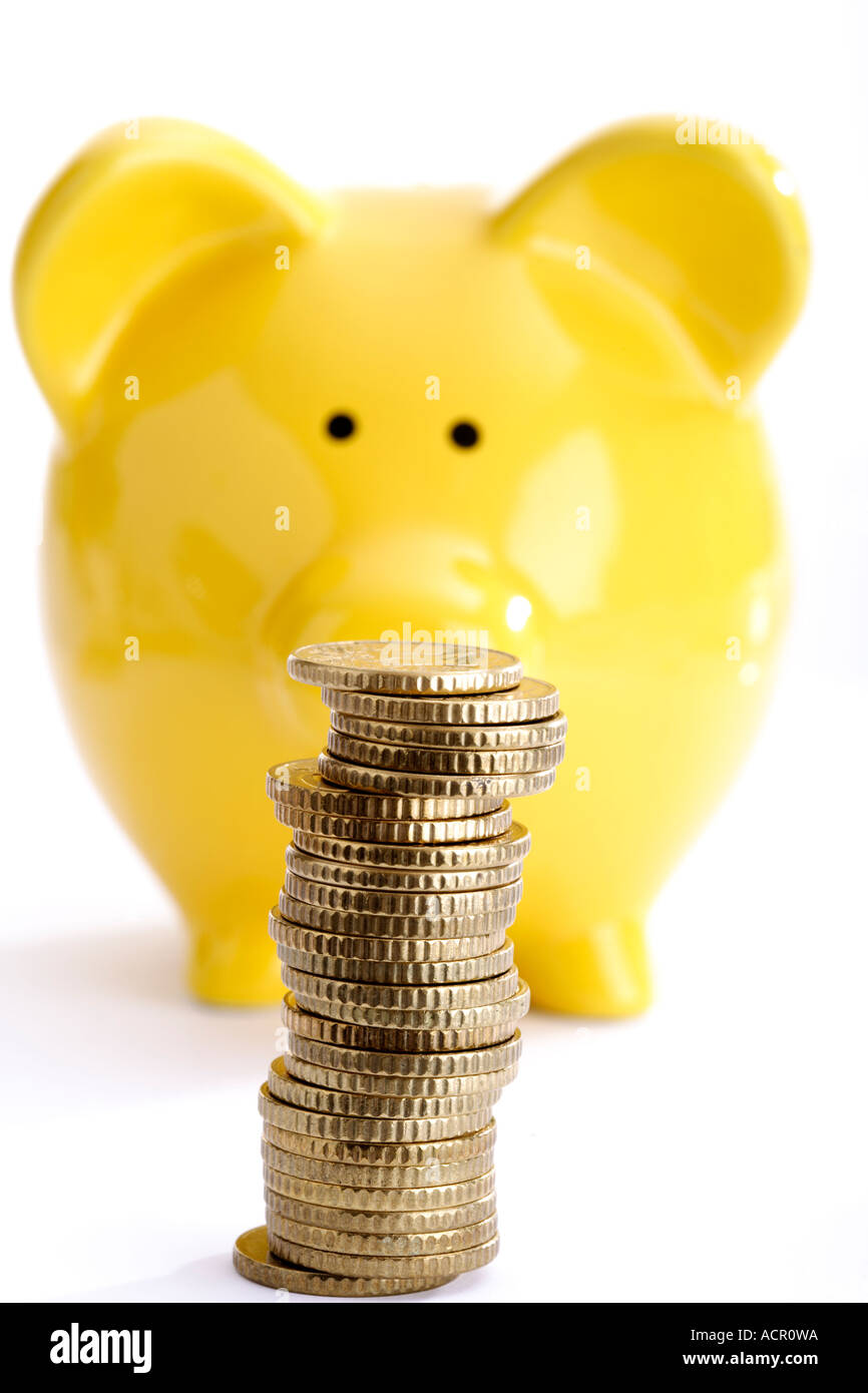 Pile of coins against yellow piggy bank Stock Photo