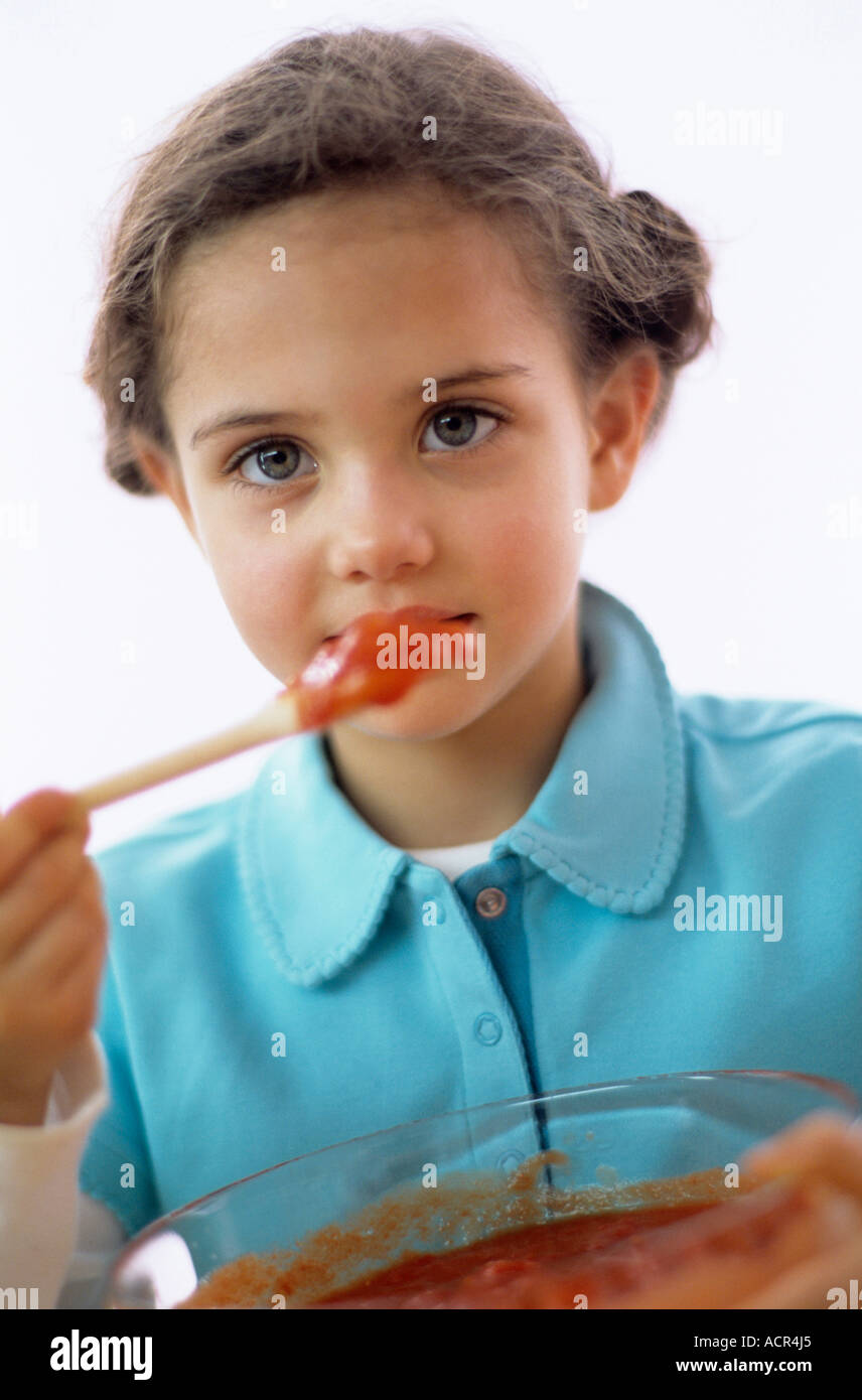 Girl (4-7) tasting tomato sauce, close-up, portrait Stock Photo