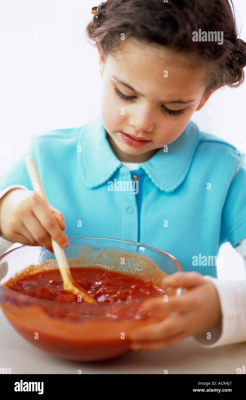 Girl (4-5) stirring tomato sauce, close-up Stock Photo