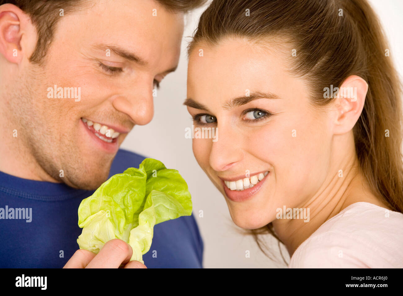 Young couple with lettuce leaf, smiling, close-up Stock Photo