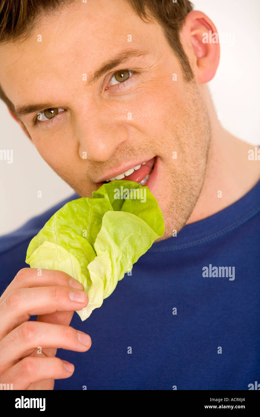 Young man eating lettuce leaf, close-up Stock Photo