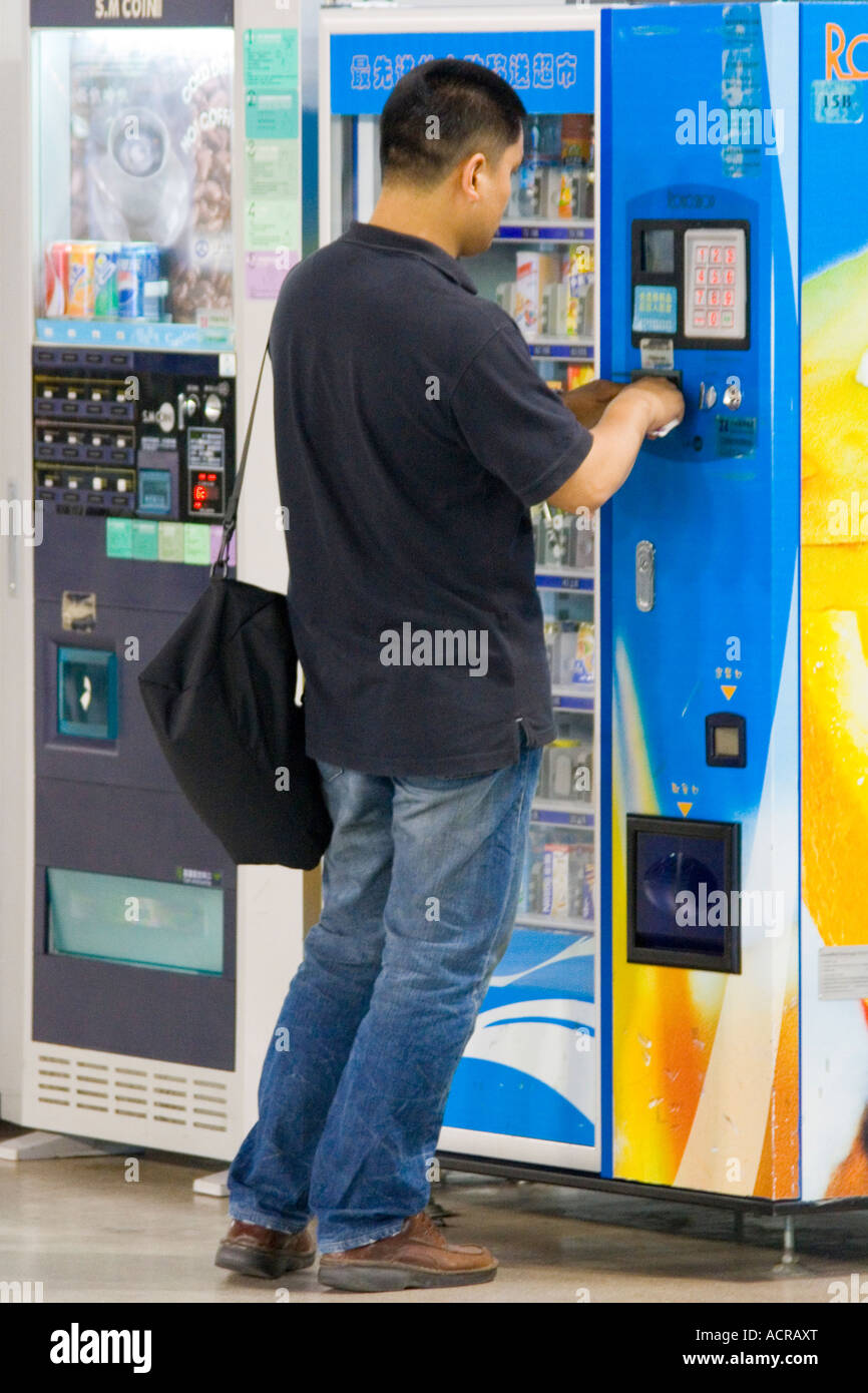 Chinese Man Buying from a Snack Vending Machine PVG Pudong International Airport Shanghai China Stock Photo