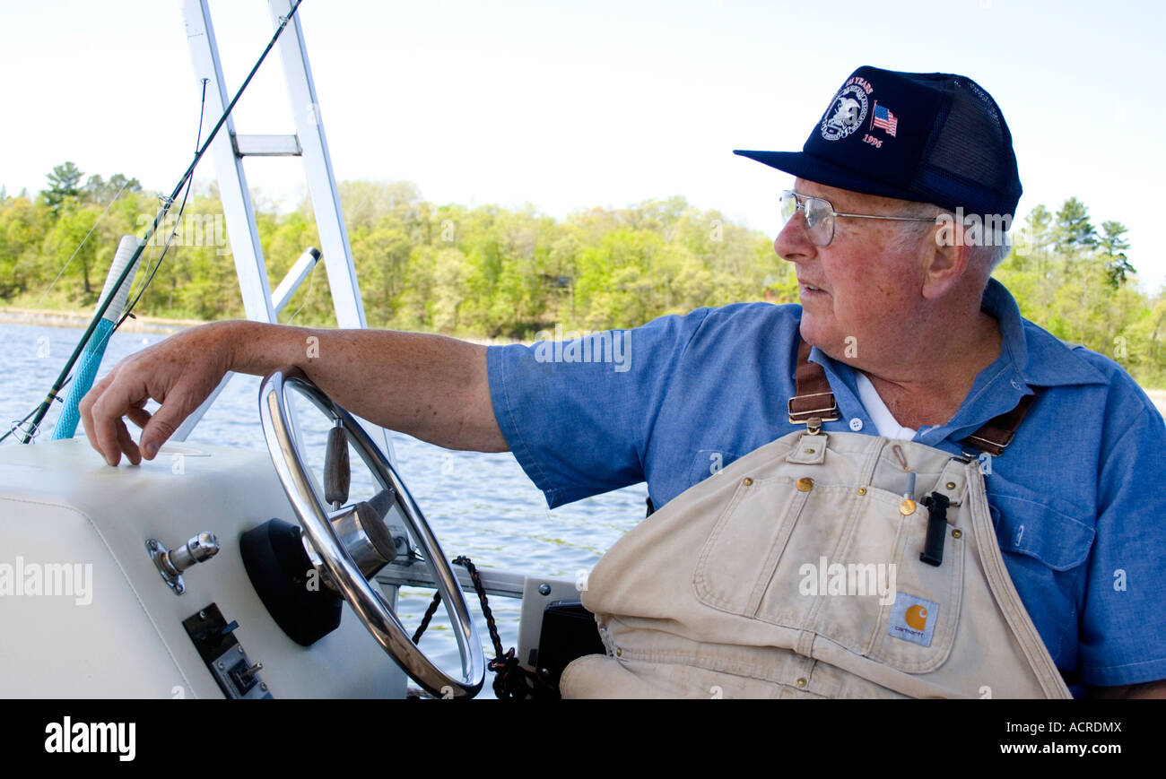 Captain Bob age 68 at the helm of the mighty pontoon boat. Gull Lake Nisswa Minnesota USA Stock Photo