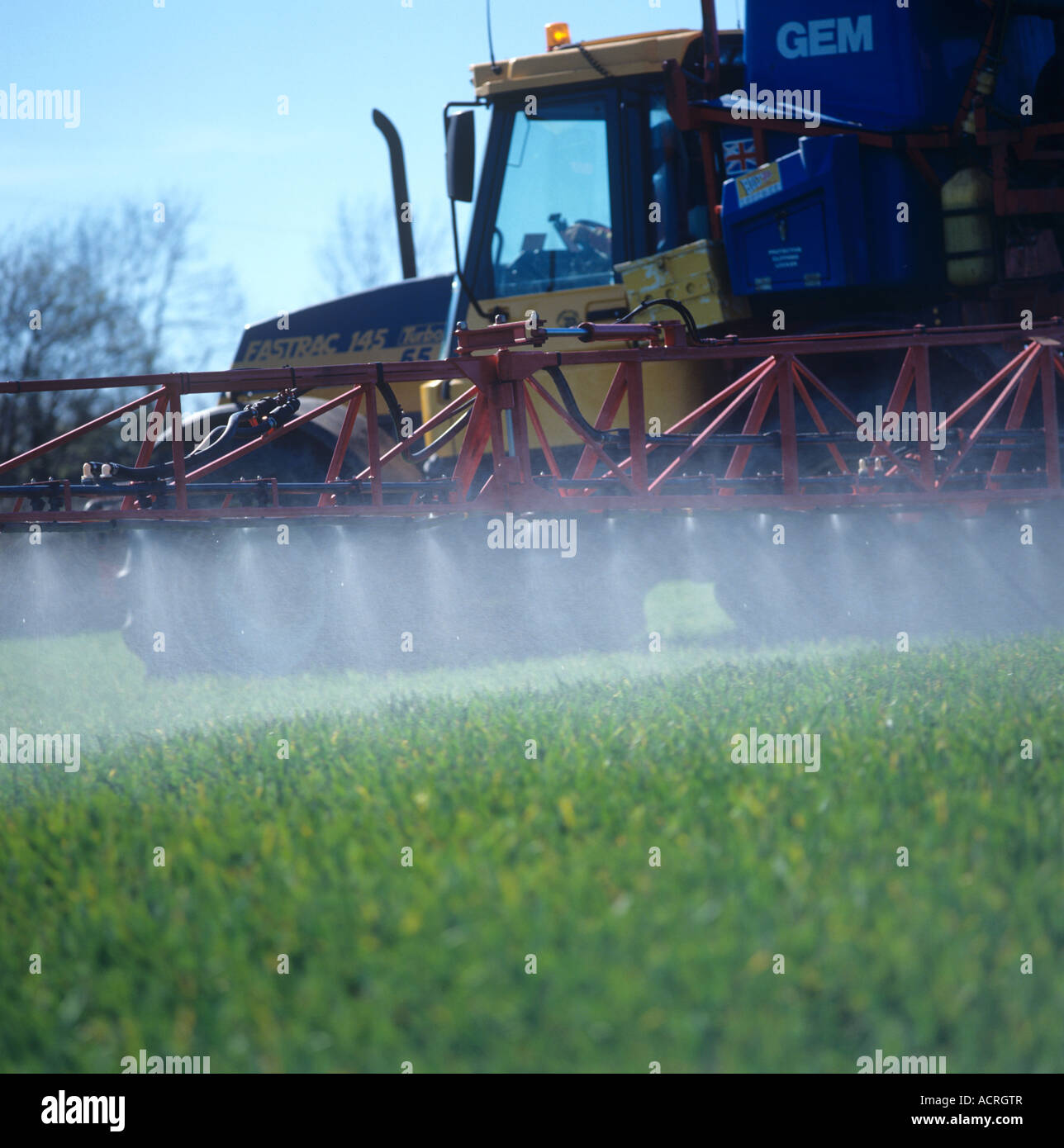 Fastrac tractor and mounted sprayer spraying young barley crop in spring Stock Photo