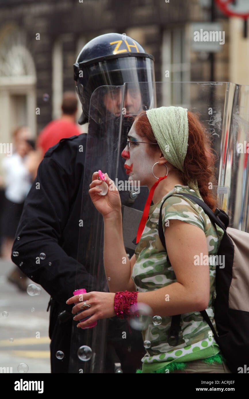 Member of the Clandestine Insurgent Rebel Clown Army blowing bubbles in front of a riot policeman Stock Photo