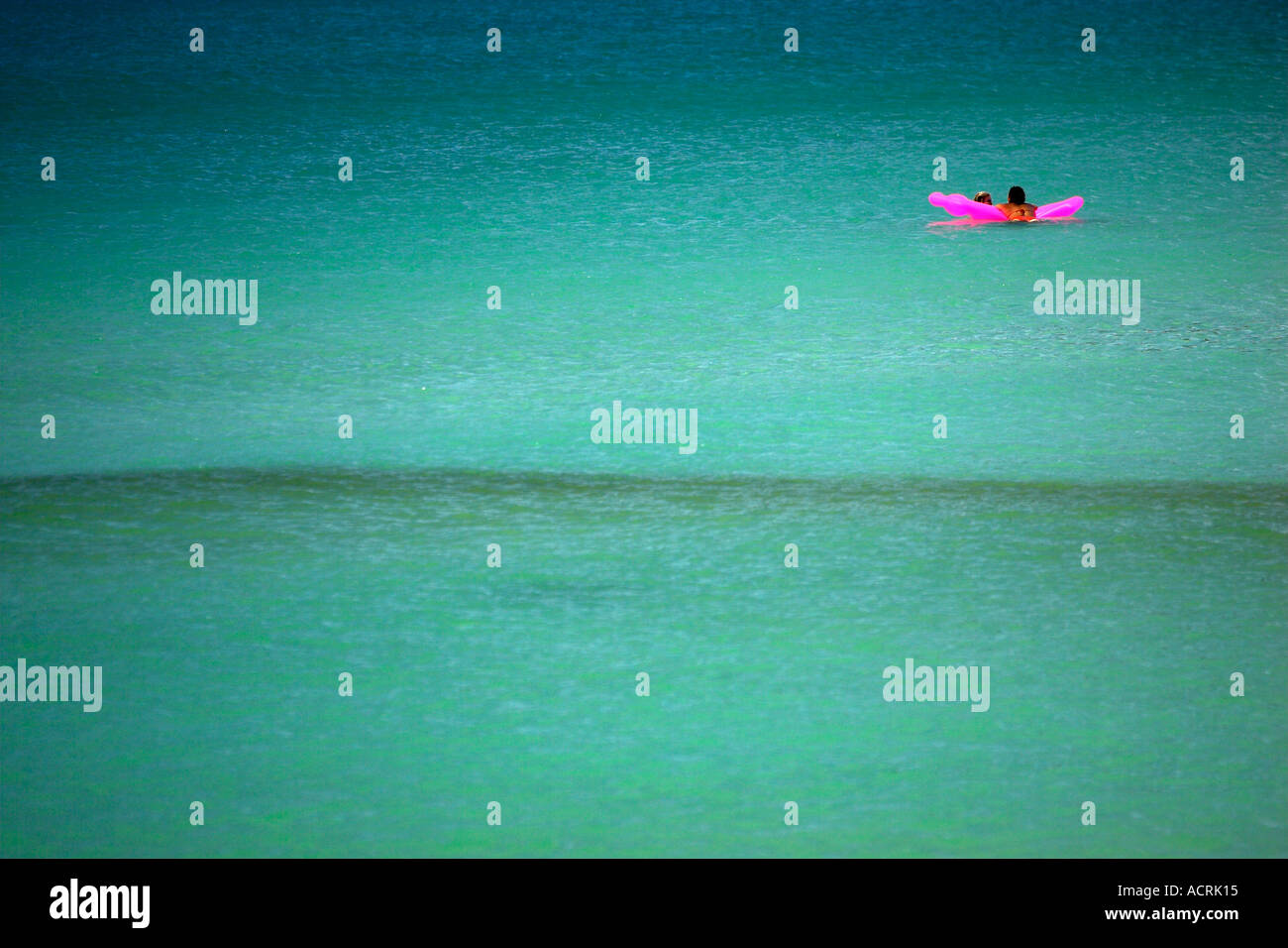 Two young women float on bright pink air bed off Sunrise Beach Ko Pha