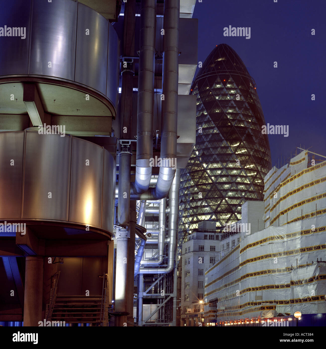 Night shot of Swiss Re Tower London inc Lloyds Building in foreground Stock Photo