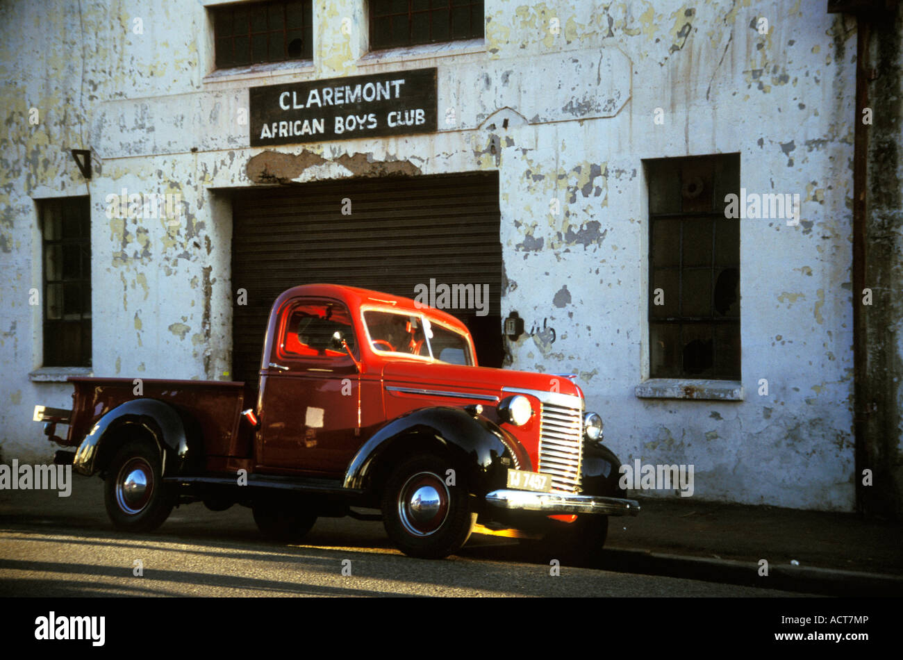 Vintage car parked outside a dilapidated building signposted Claremont African Boys Club Western Cape South Africa Stock Photo