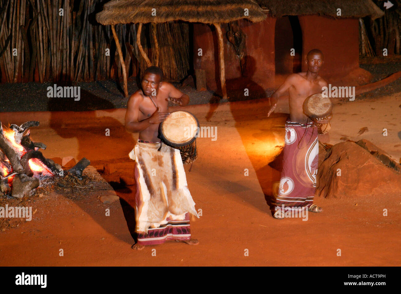 Drummers play at an evening dance show presented at the fireside in an outdoor boma at the Shangana cultural village Stock Photo