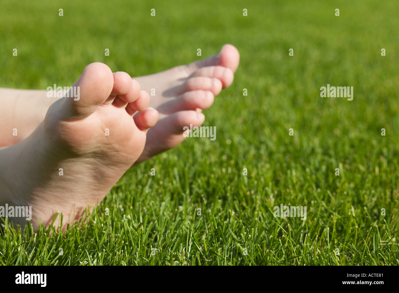 Boy s bare feet on grass lawn Stock Photo Alamy