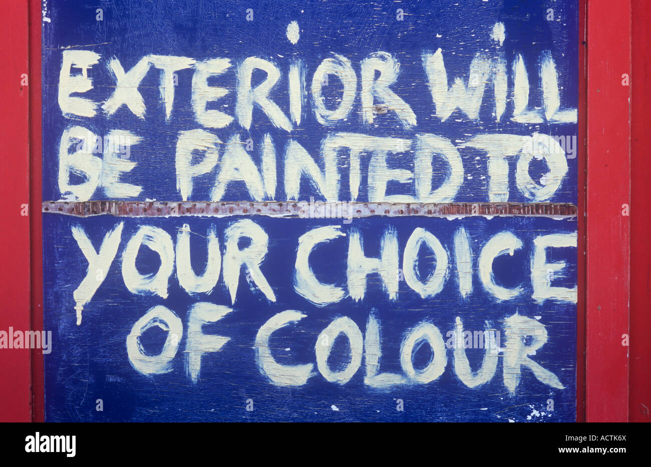 Sign painted freehand in cream on dark blue background with red edges stating Exterior will be painted to your choice of colour Stock Photo