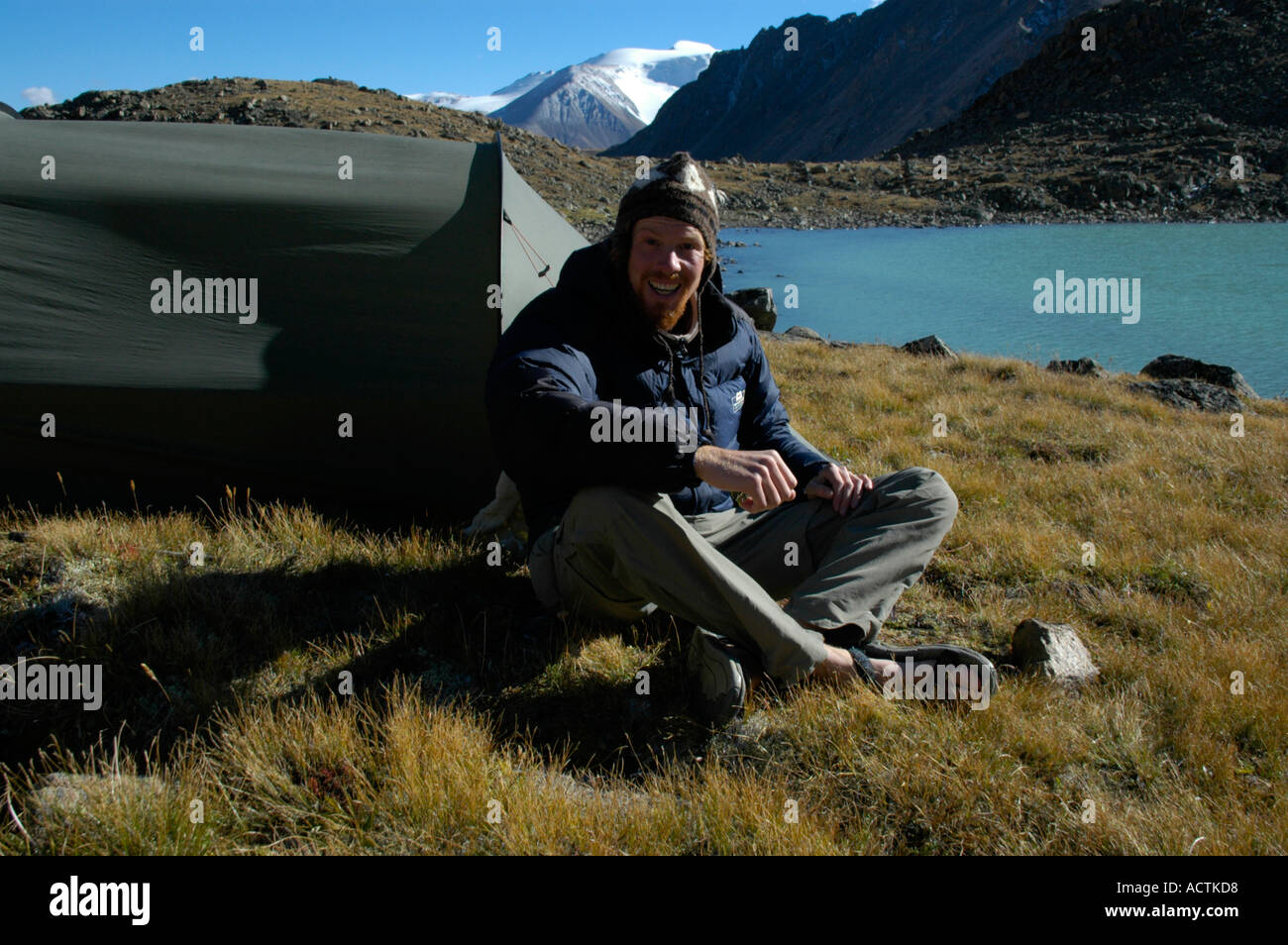 MR Mountaineer sits at the tent at a blue mountain lake Kharkhiraa Mongolian Altai near Ulaangom Uvs Aymag Mongolia Stock Photo