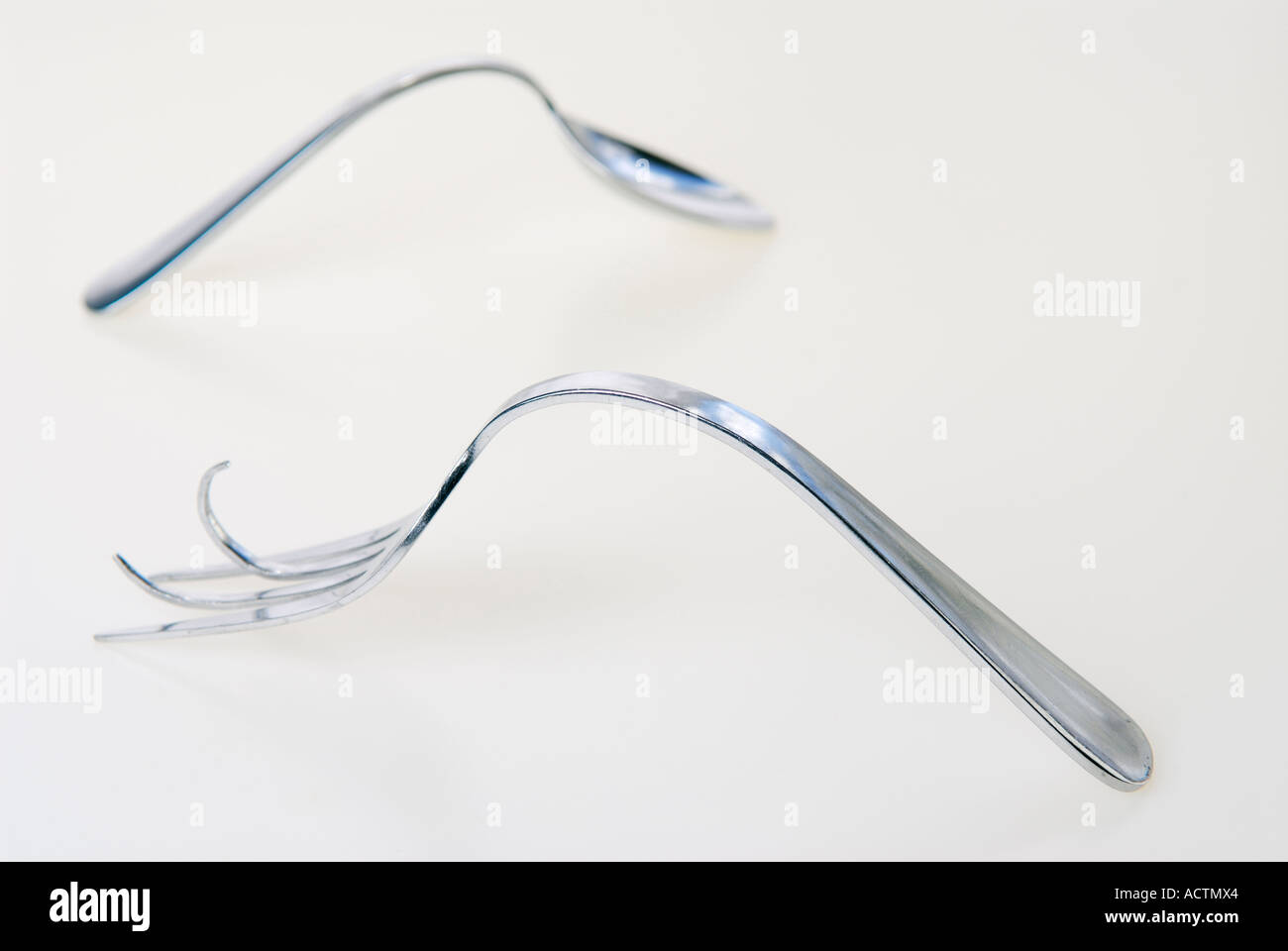 Bent spoon and fork after illusionist trick on white background Stock