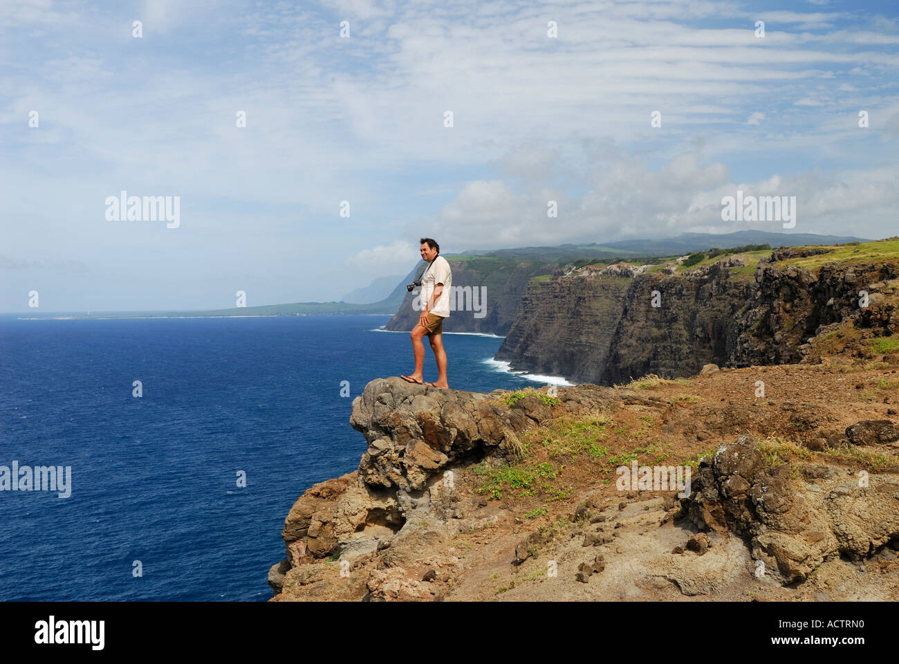 Tourist standing on precipice on high sea cliffs of Kalaupapa Molokai Island Hawaii Stock Photo