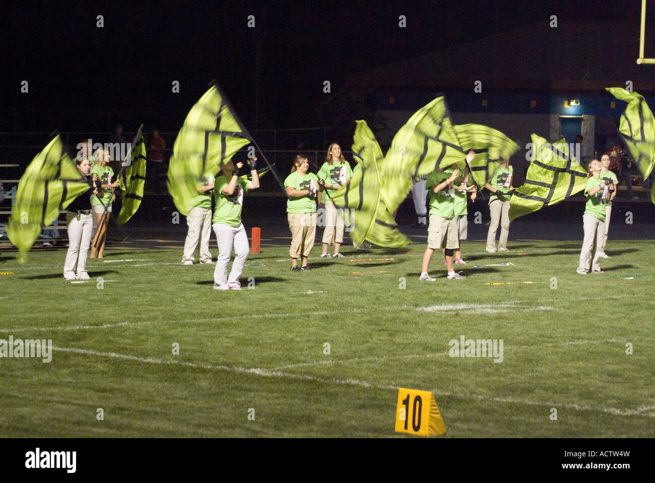 CHEER LEADING GROUP DRESSED IN PARROT GREEN IS DISPLAYING A SHOW WITH FLAGS IN THEIR HANDS Stock Photo