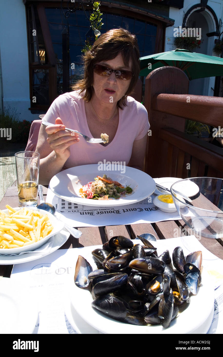 dh Old Court House Inn ST AUBINS JERSEY Dinner woman eating seafood mussels al fresco lunch restaurant channel island tourist outdoors table plate Stock Photo