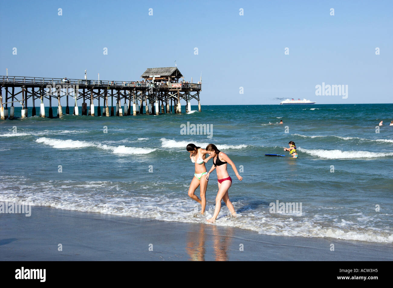 The Cocoa Beach Florida pier with cruise ship, waves and two girls