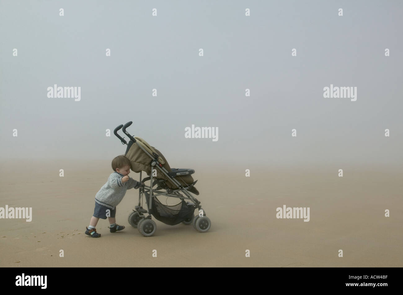 child playing on foggy beach with pram Stock Photo Alamy