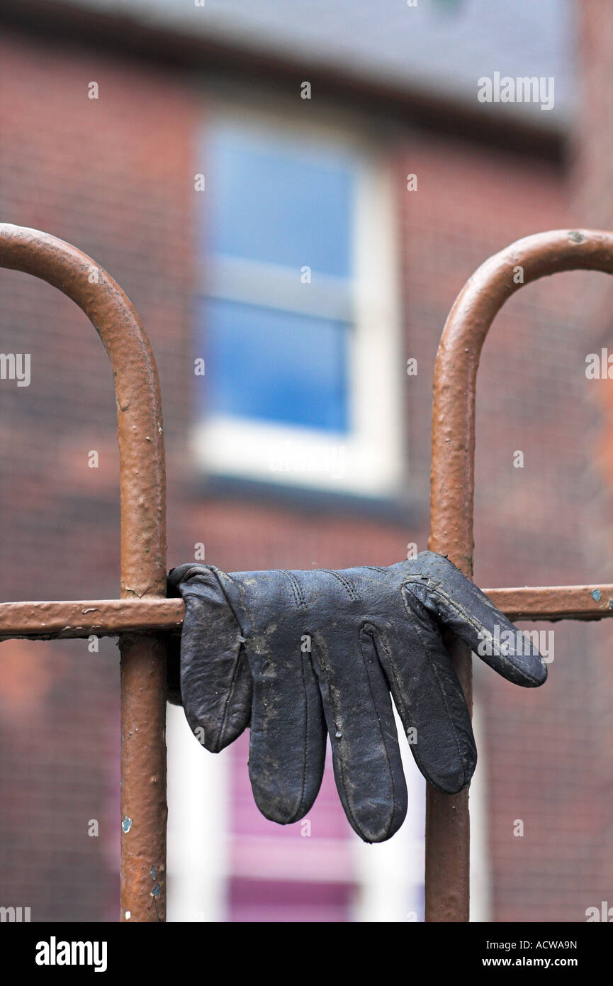 An old leather glove, lays discarded draped over some railings Stock