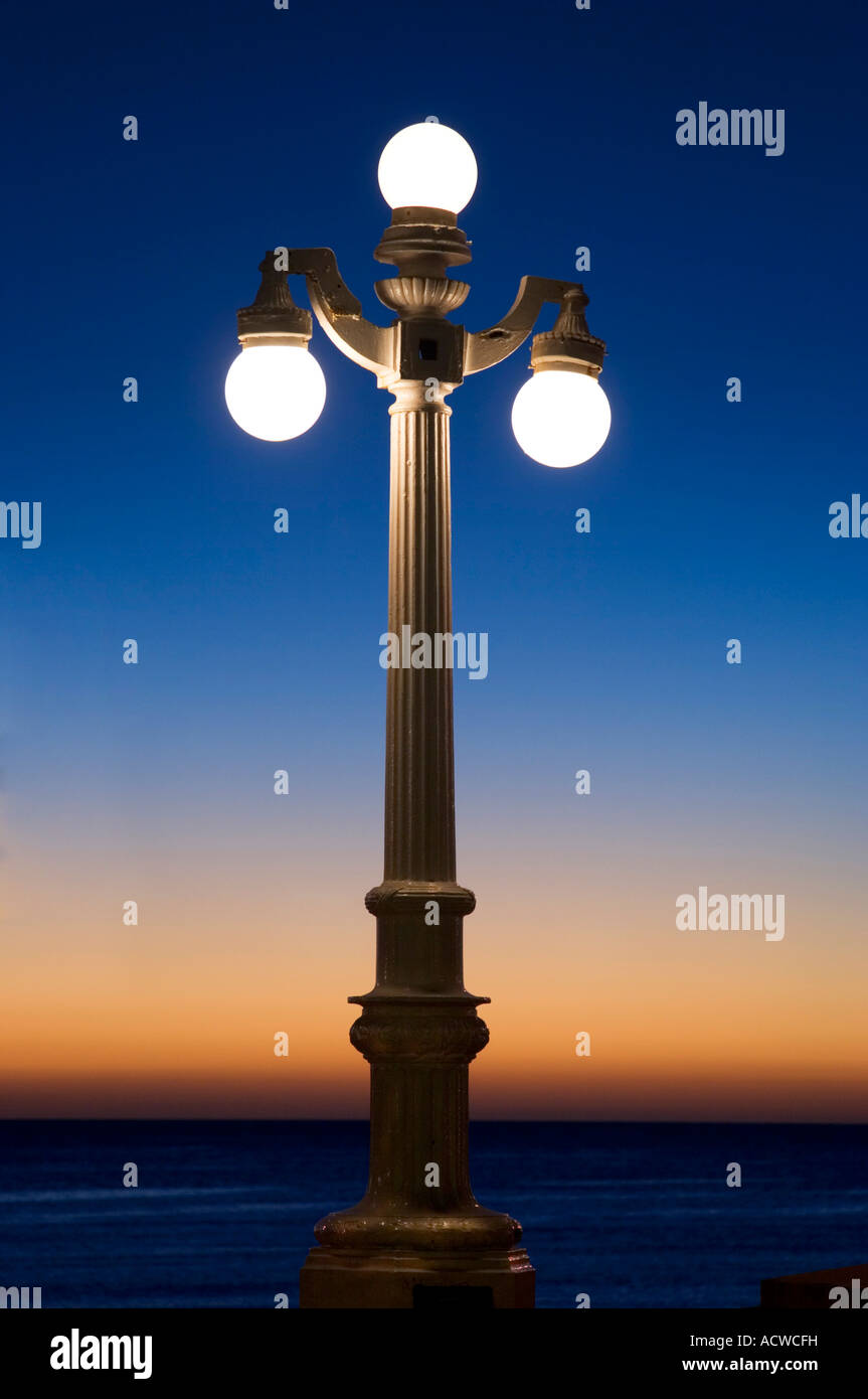 Old fashion lamppost with lit bulbs at sunset Stock Photo