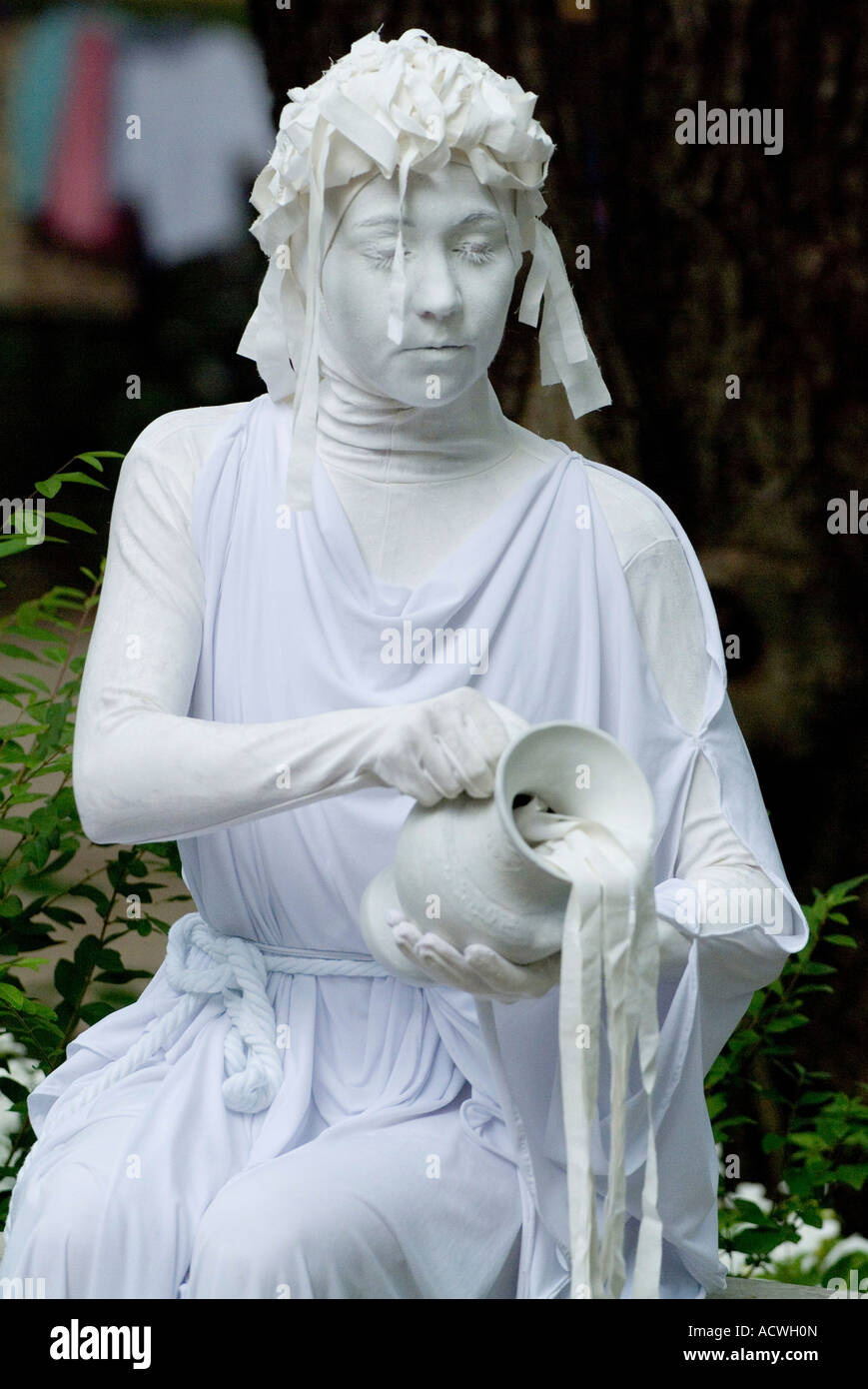 A WOMAN IS MIMING AS A WHITE MARBLE STATUE POURING WATER OUT OF A JUG