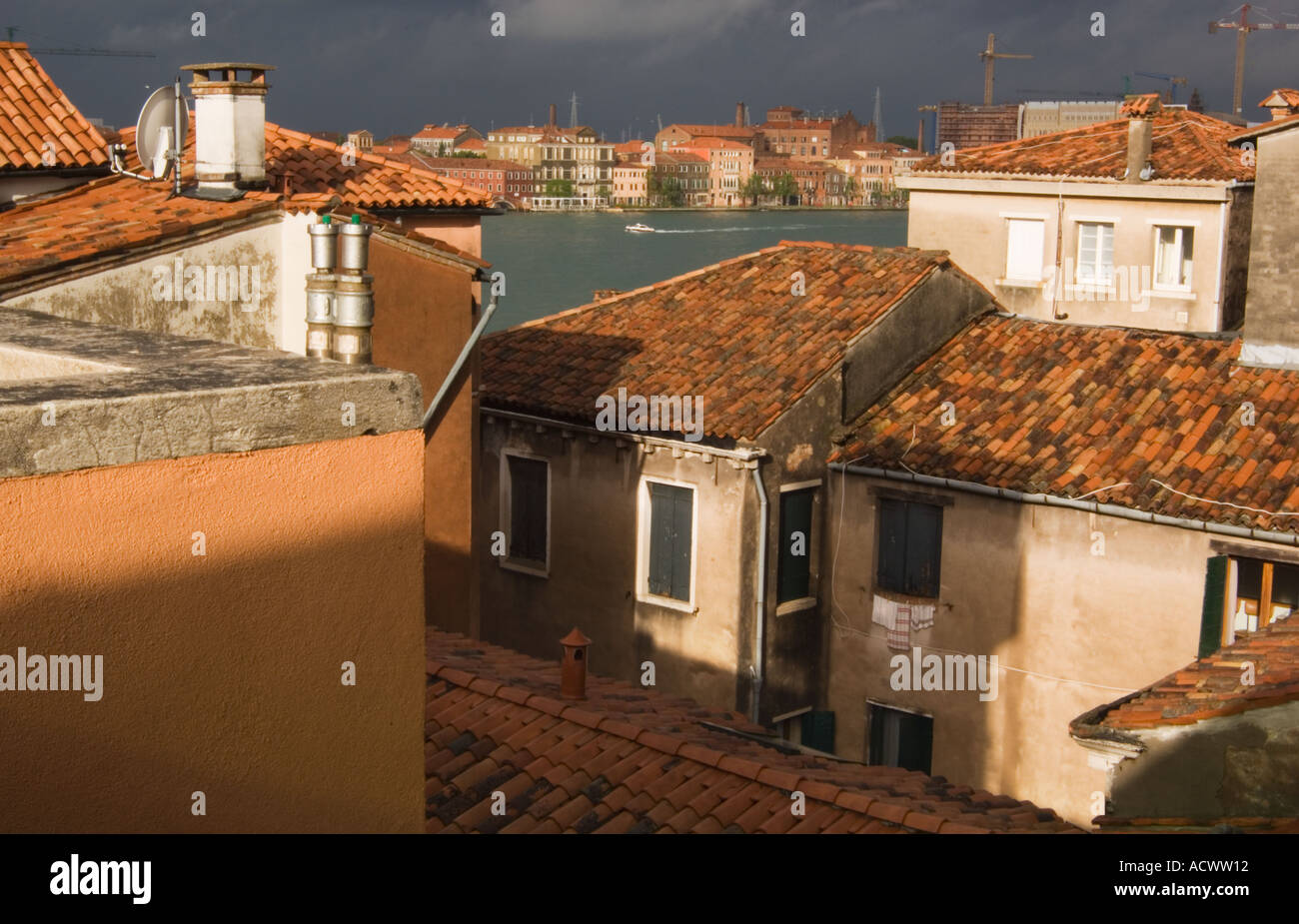 looking over rooftops in Venice Italy with terra cotta shingles and chimneys cranes sattelite dishes and canal in background Stock Photo