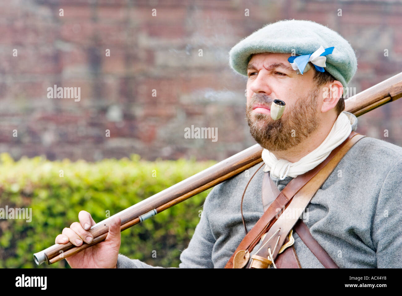 Covenanter soldier stands smoking pipe with musket over shoulder Stock