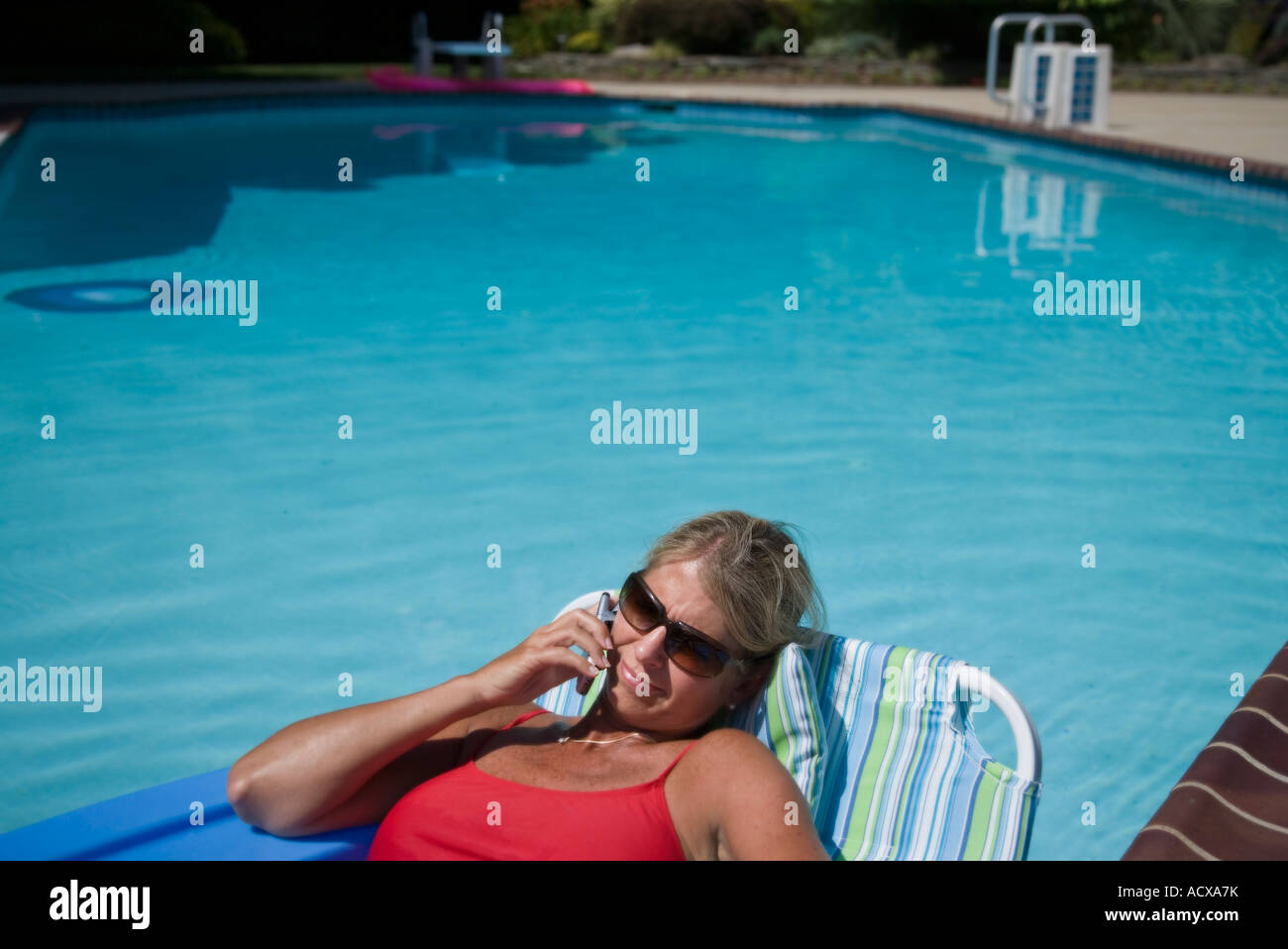 Woman sitting on a lounge by the pool Stock Photo
