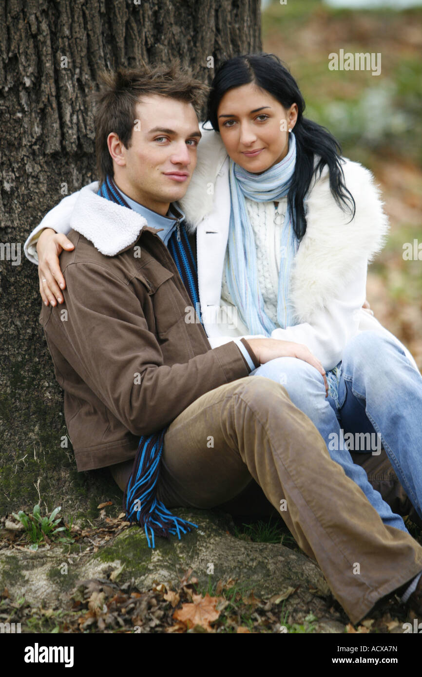 A young couple is sitting on the ground in the autumn forest lifestyle ...