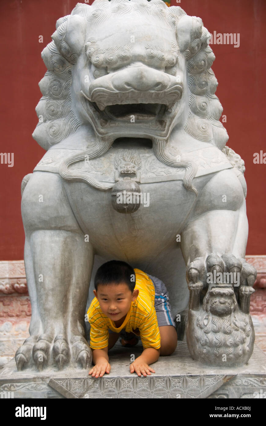 Young boy climbing through stone lion at Beihai Park Beijing China 2007 Stock Photo