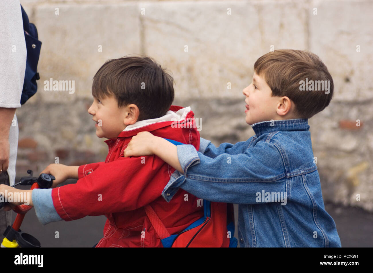 Editorial use only No model release two small smiling caucasian boys riding tandem on a bicycle without helmet in Taormina Stock Photo