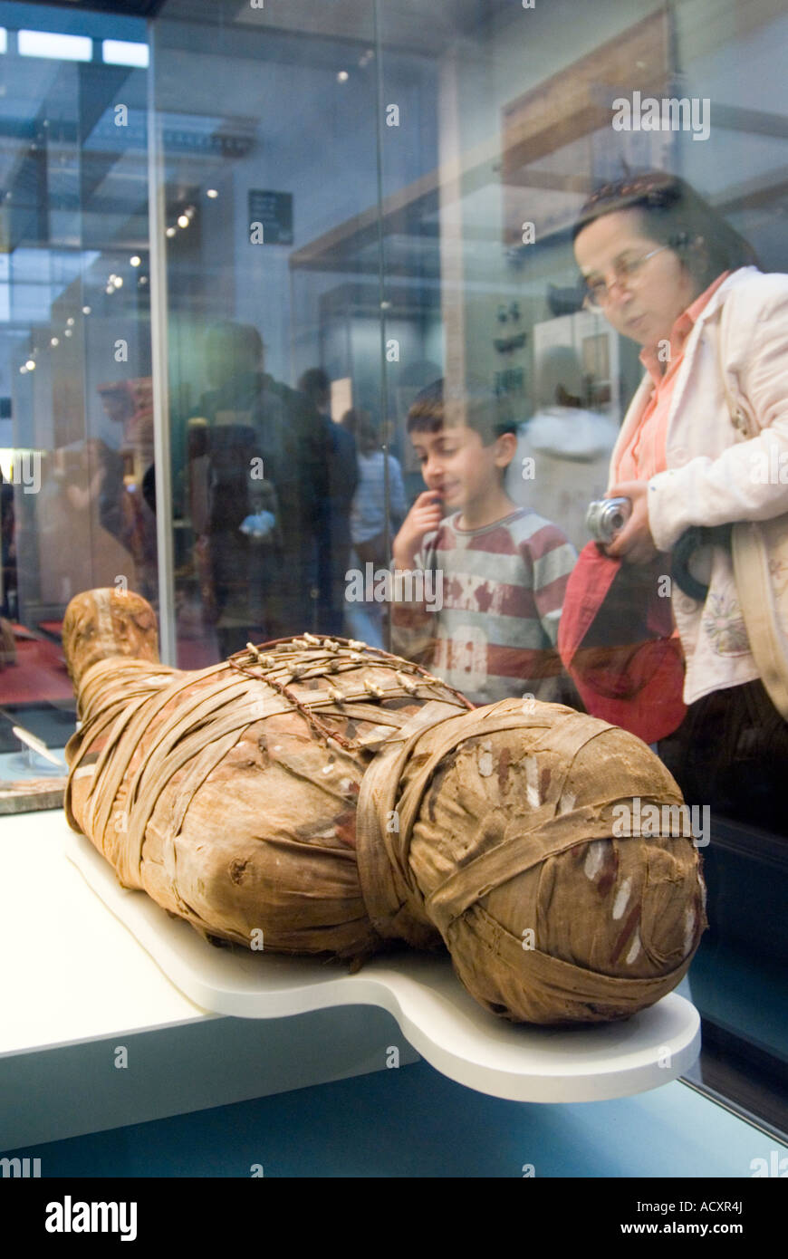 Visitors looking at an ancient Egyptian mummy in the British Museum, London, England, UK Stock Photo