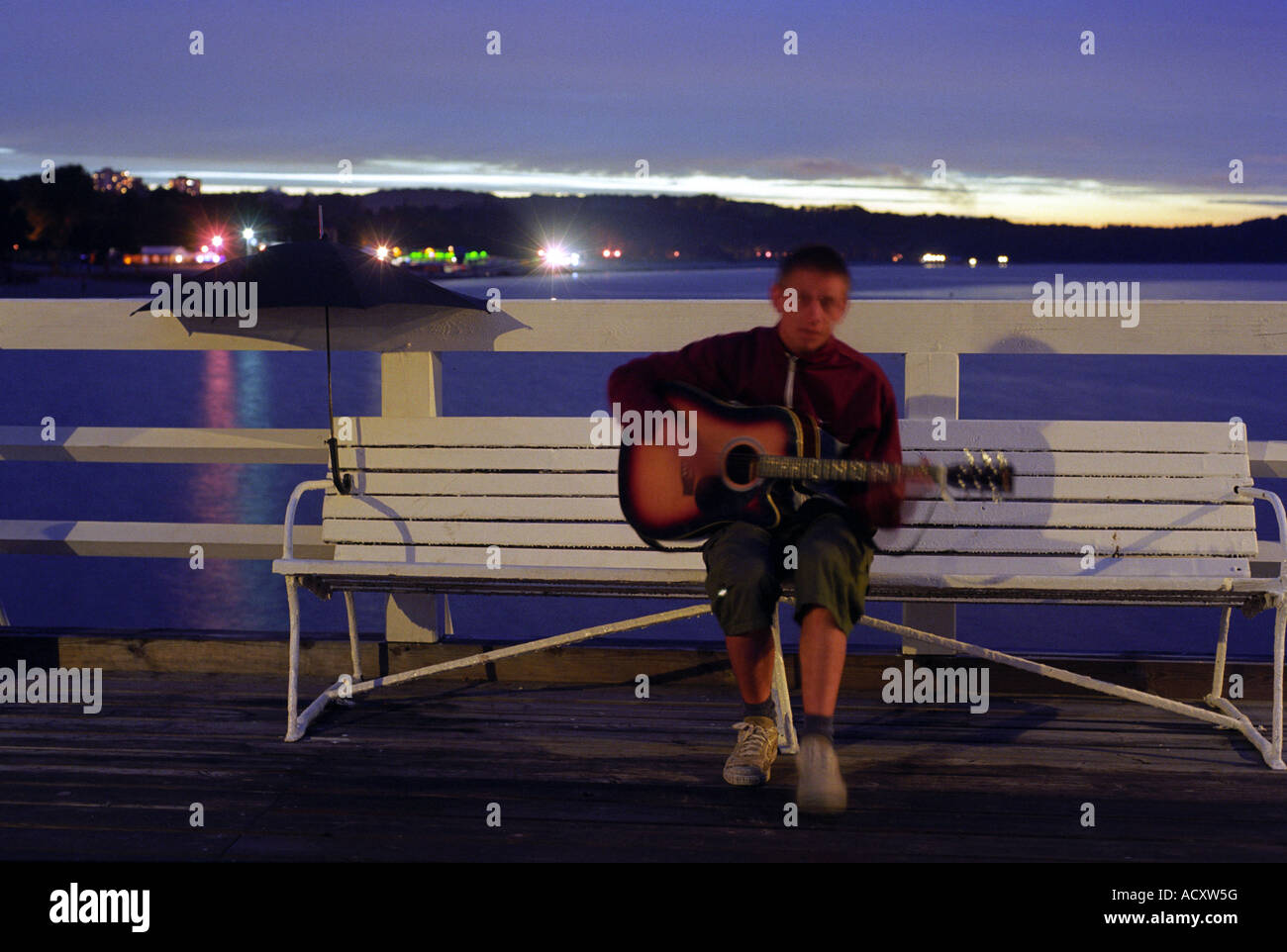 Boy playing guitar on a bench on the pier in Sopot, Poland Stock Photo