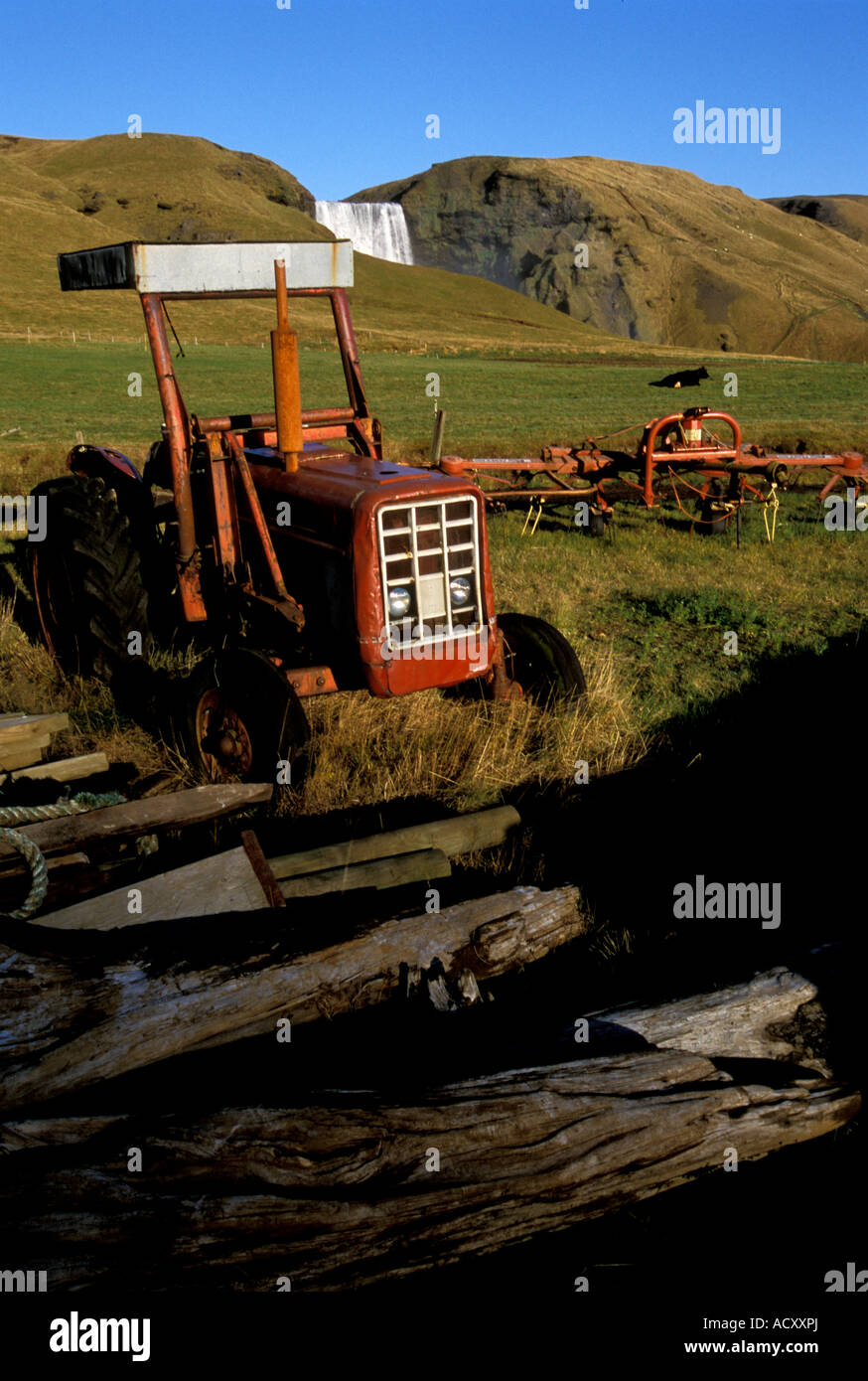 Skógar Iceland A red tractor sits on a farm next to Skogar Falls  Stock Photo