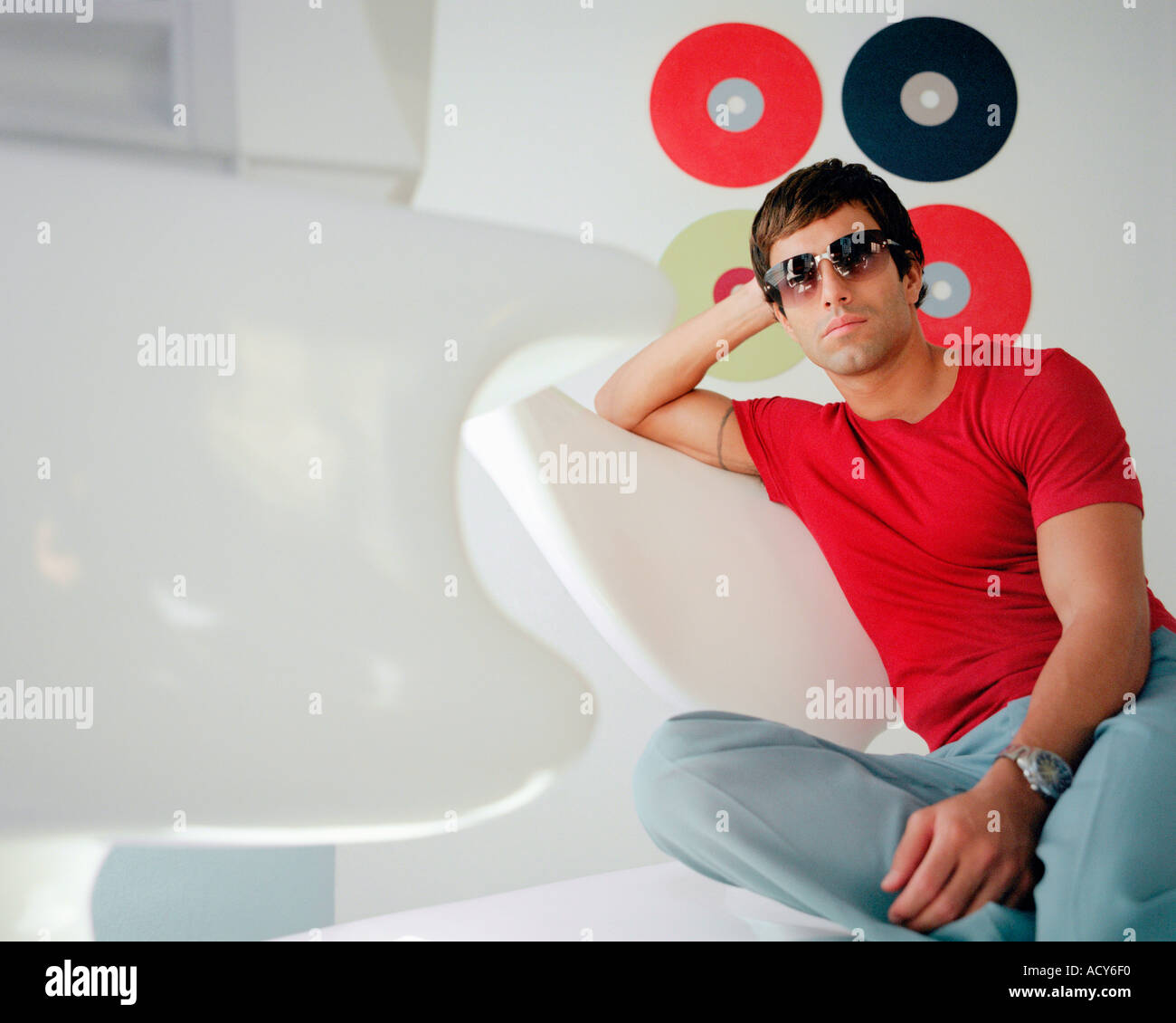 young man wearing sunglasses sitting in stylish contemporary interior Stock Photo