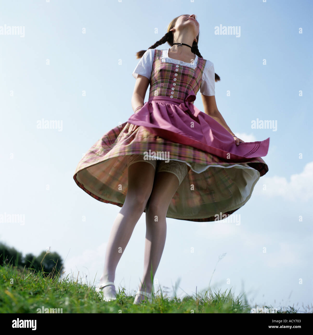 young woman in traditional German Bavarian dress dancing with lifted skirt Stock Photo