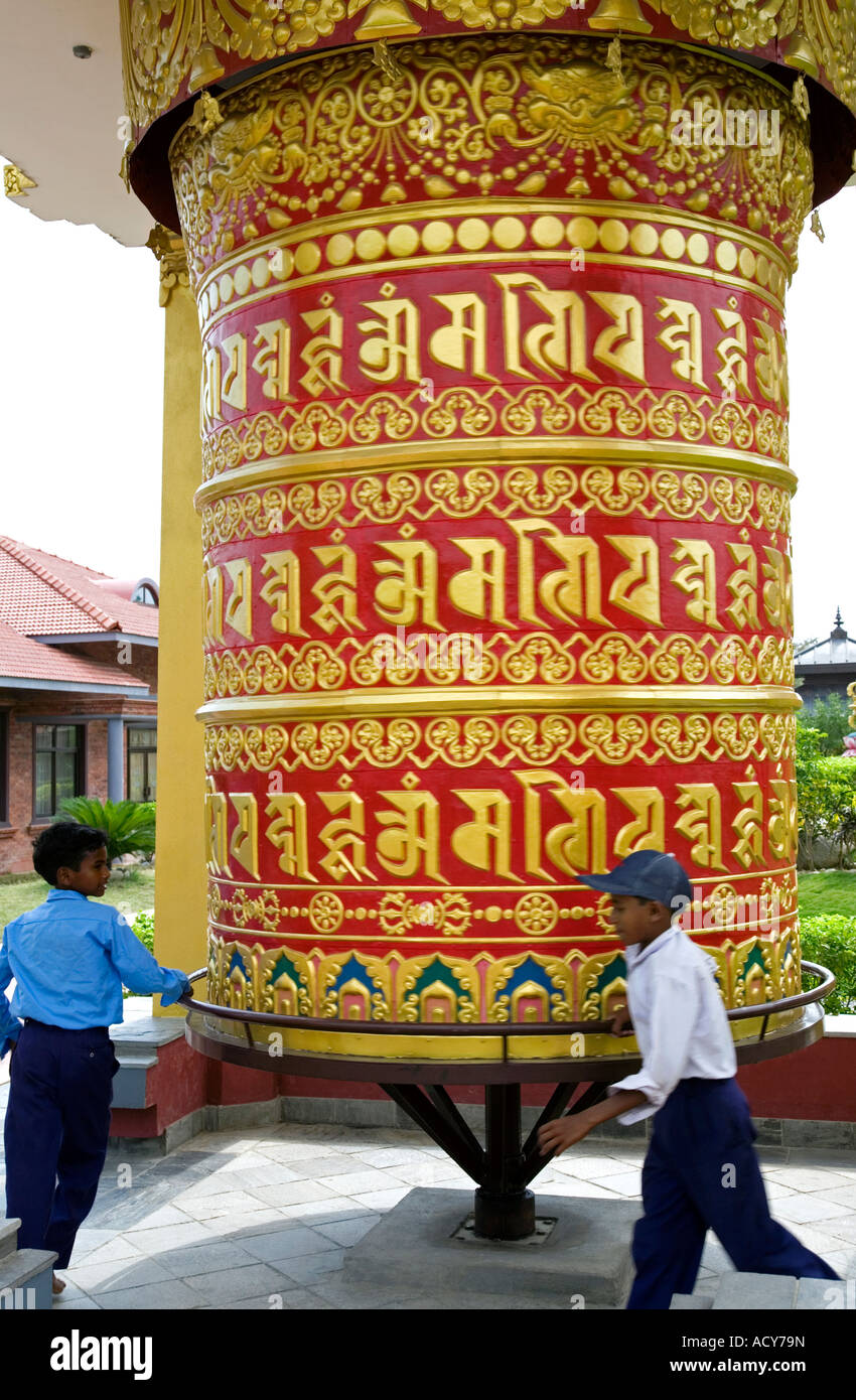 Children spinning a big prayer wheel. German Buddhist monastery. Lumbini. Nepal Stock Photo