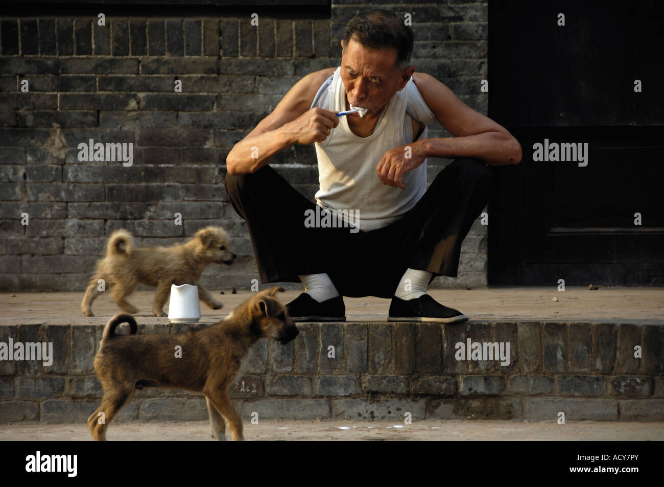 An elder man brushes his teeth on roadside in Pingyao Shanxi province China 7 Jun 2007 Stock Photo