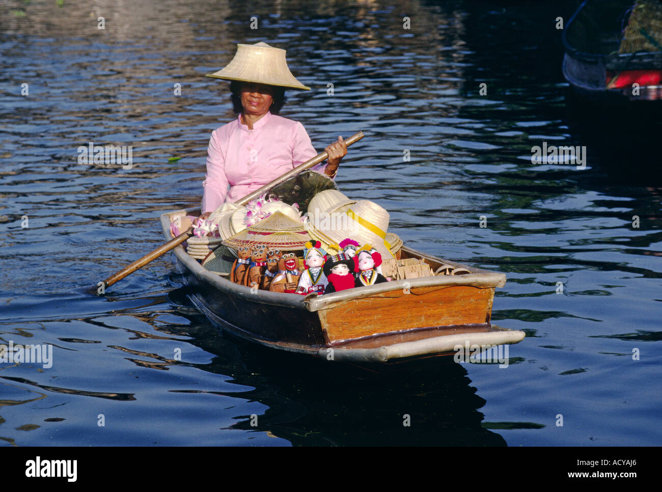 Thai woman sells hats dolls from her boat at the FLOATING MARKET on KLONG DAO KANONG BANGKOK THAILAND Stock Photo