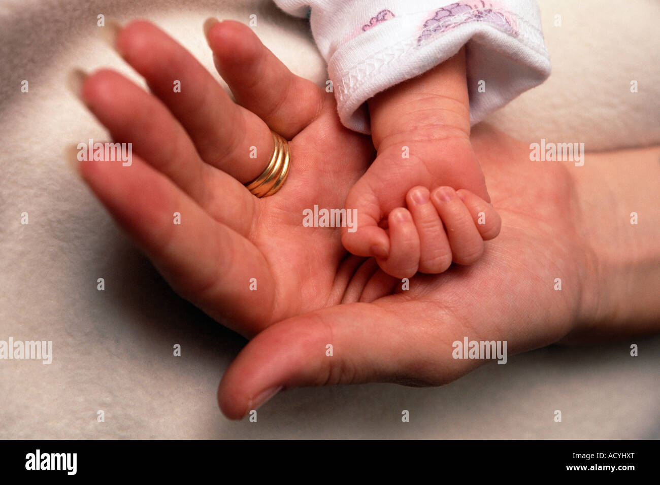 A baby girl's hand lies cradled in her mother's open palm. Stock Photo