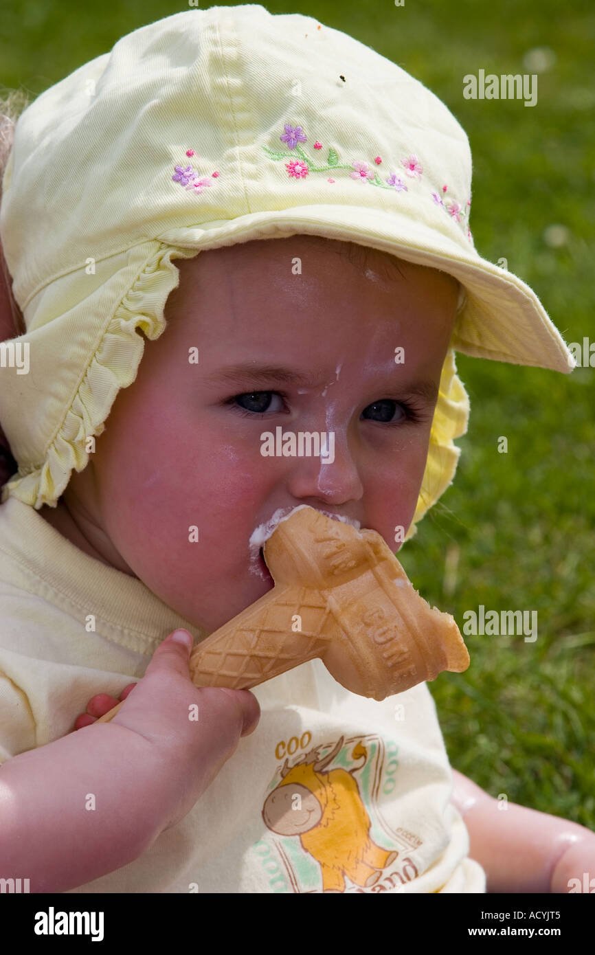 Little girl wearing a sun hat sun cream and enjoying an ice cream Stock