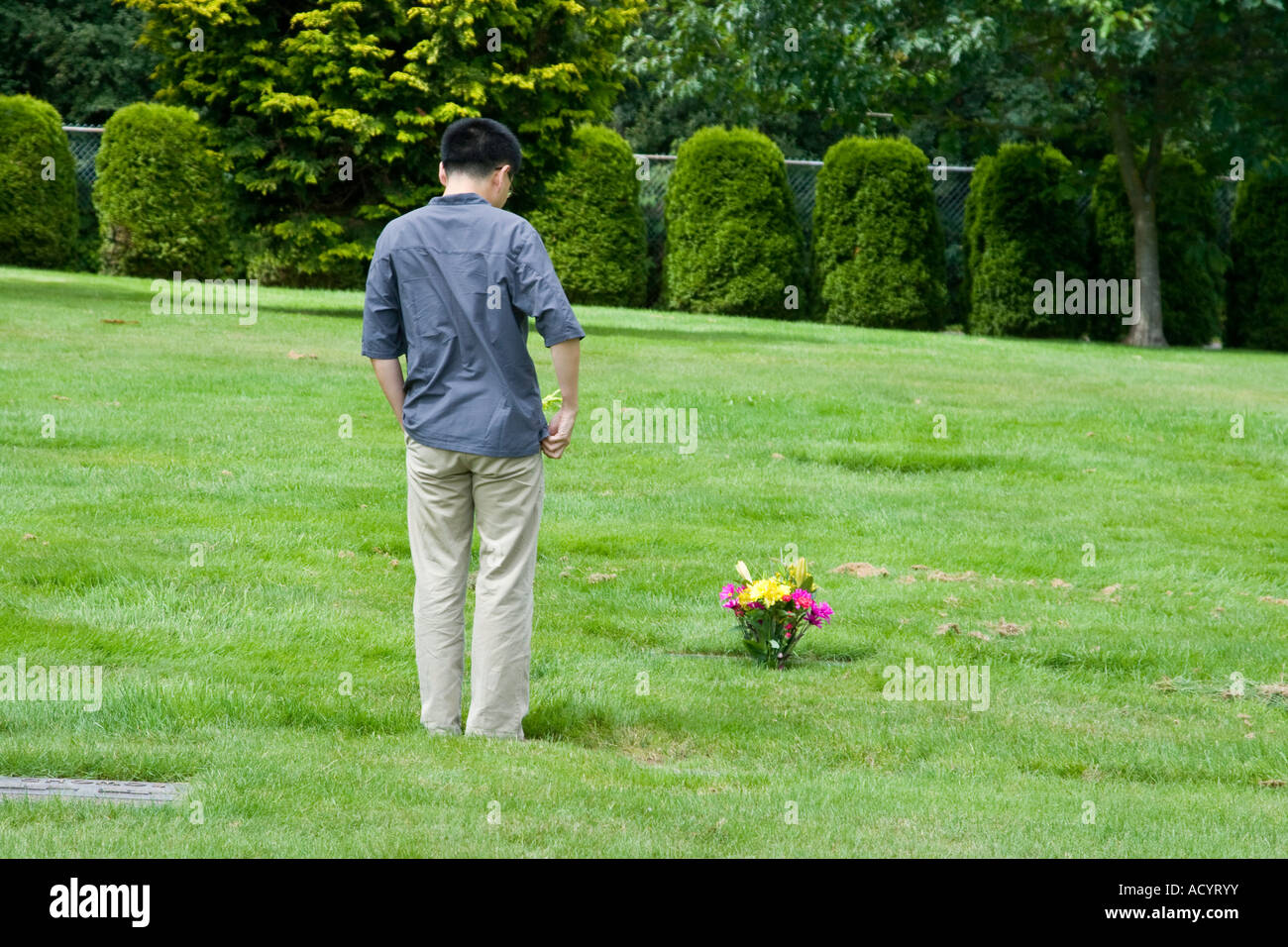 Asian Man Visiting Grave of Dead Relative at the Cemetery Stock Photo