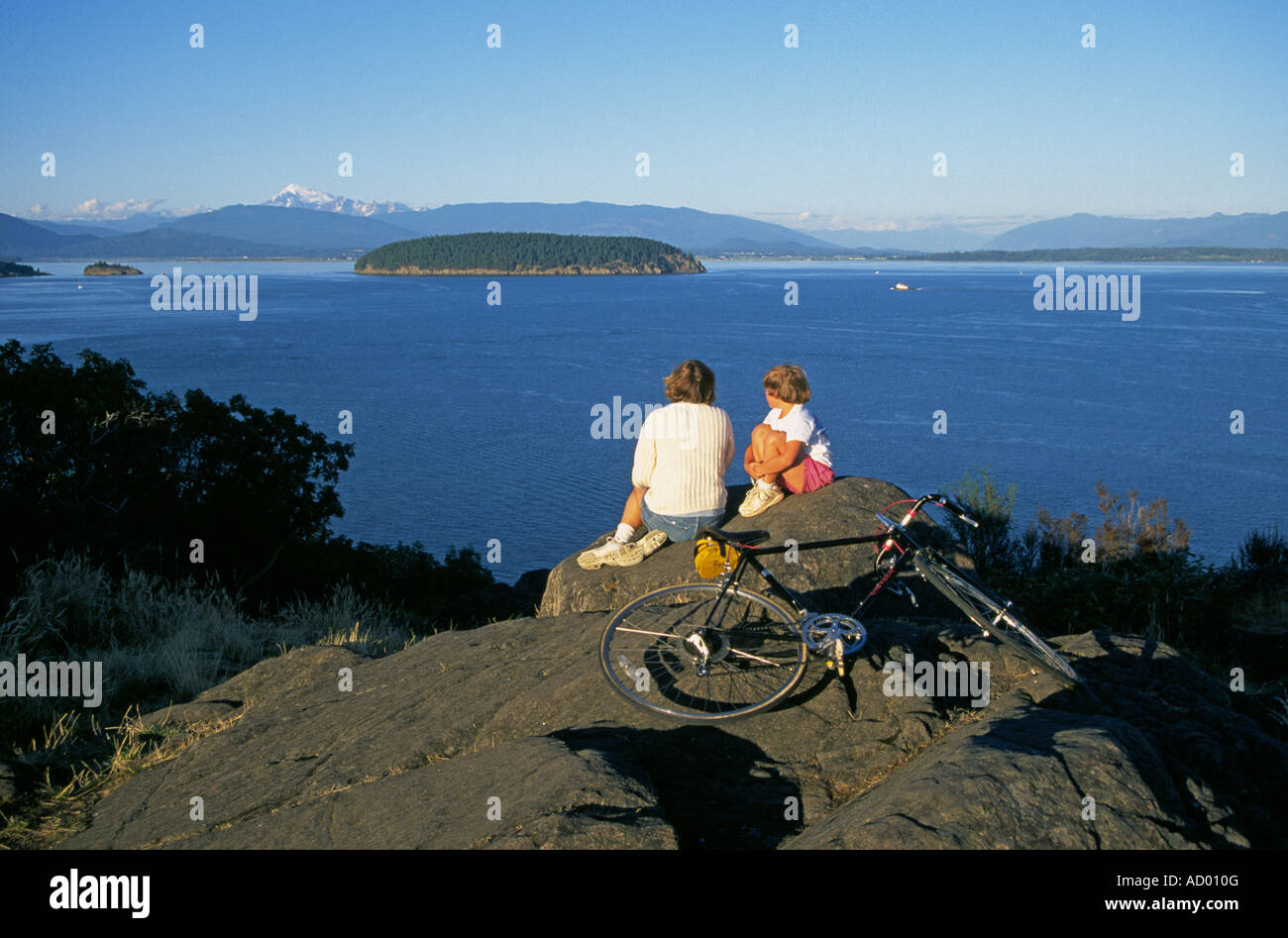 A mother and daughter on bicycles on the island of anacortes look for whales in Puget Sound in the San Juan Islands, Washington. Stock Photo
