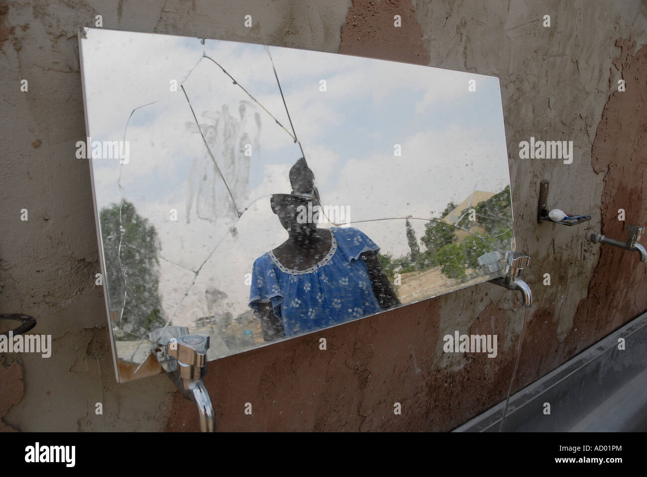 African asylum seeker is reflected in a broken mirror at Kadesh Barnea settlement, southern Israel. Stock Photo