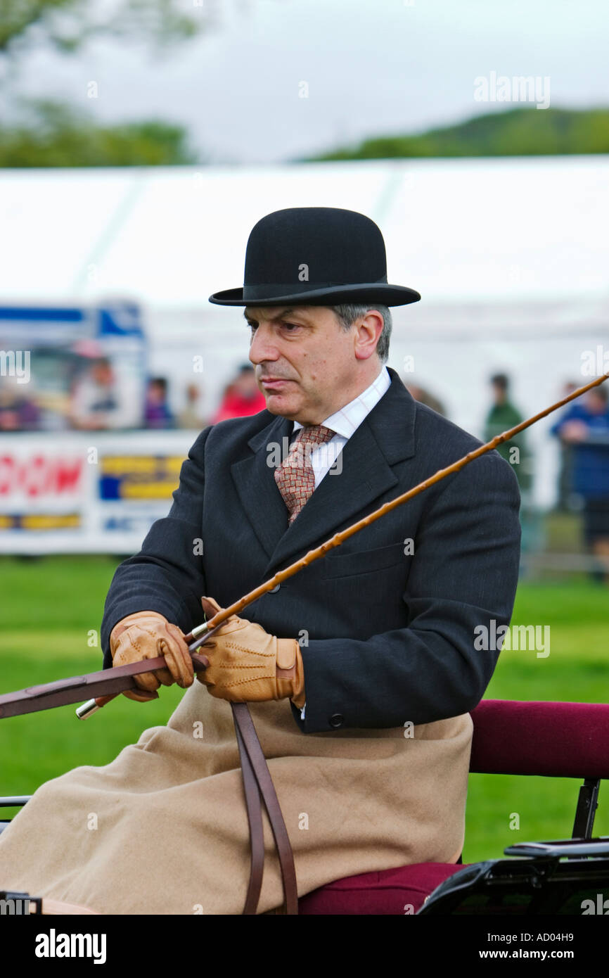 Man in bowler hat driving carriage in show ring at agricultural show